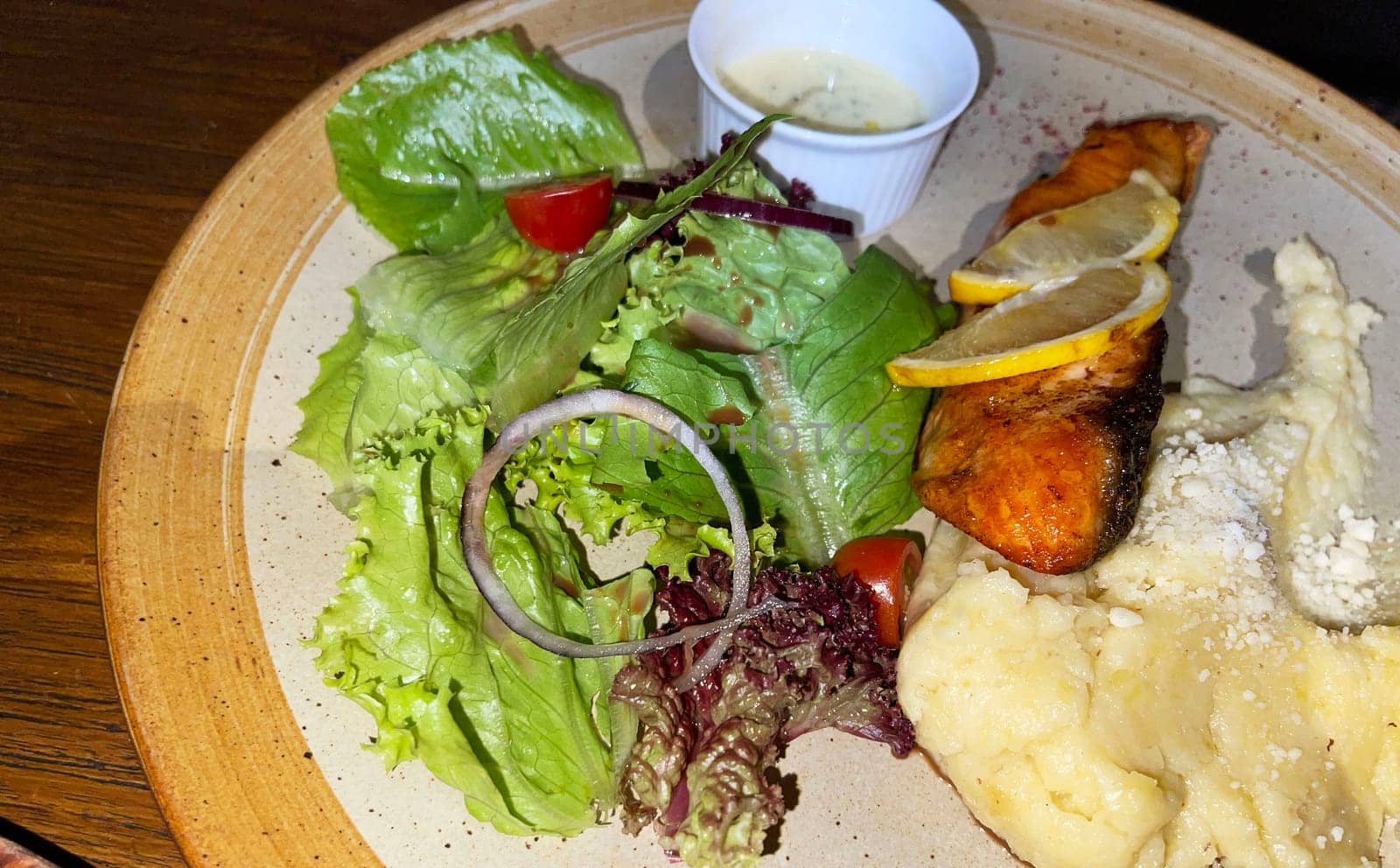 smoked grilled salmon fish served with salad and mash potatoes with lemons on top, served in plate perfect meal