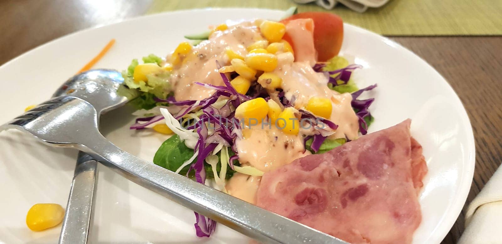 delicious breakfast, ham and fresh summer salad on white plate, on wooden table, view from above, good for your multimedia content background