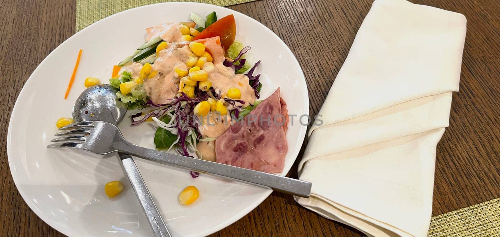 delicious breakfast, ham and fresh summer salad on white plate, on wooden table, view from above, good for your multimedia content background