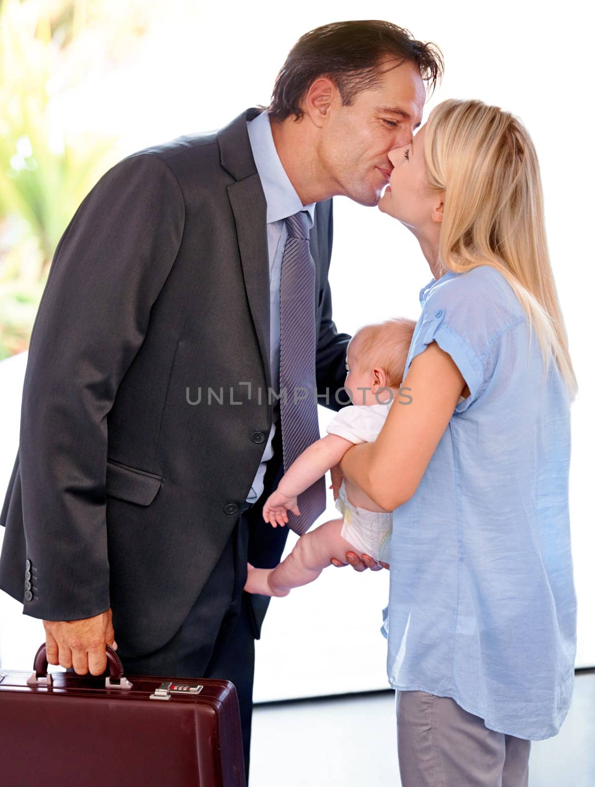 Businessman, family and parents kiss baby, love in relationship or welcome home on valentines day. Kid, toddler and mother with father in romance for connection, greeting or arrival together in house by YuriArcurs