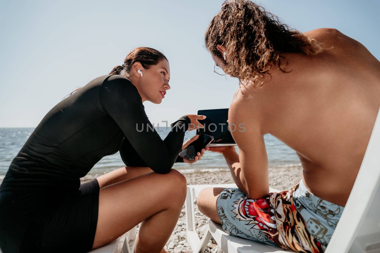 Man woman laptop sea. Working remotely on seashore. Happy successful couple, freelancers working on sea beach, relieves stress from work to restore life balance. Freelance, remote work on vacation by panophotograph