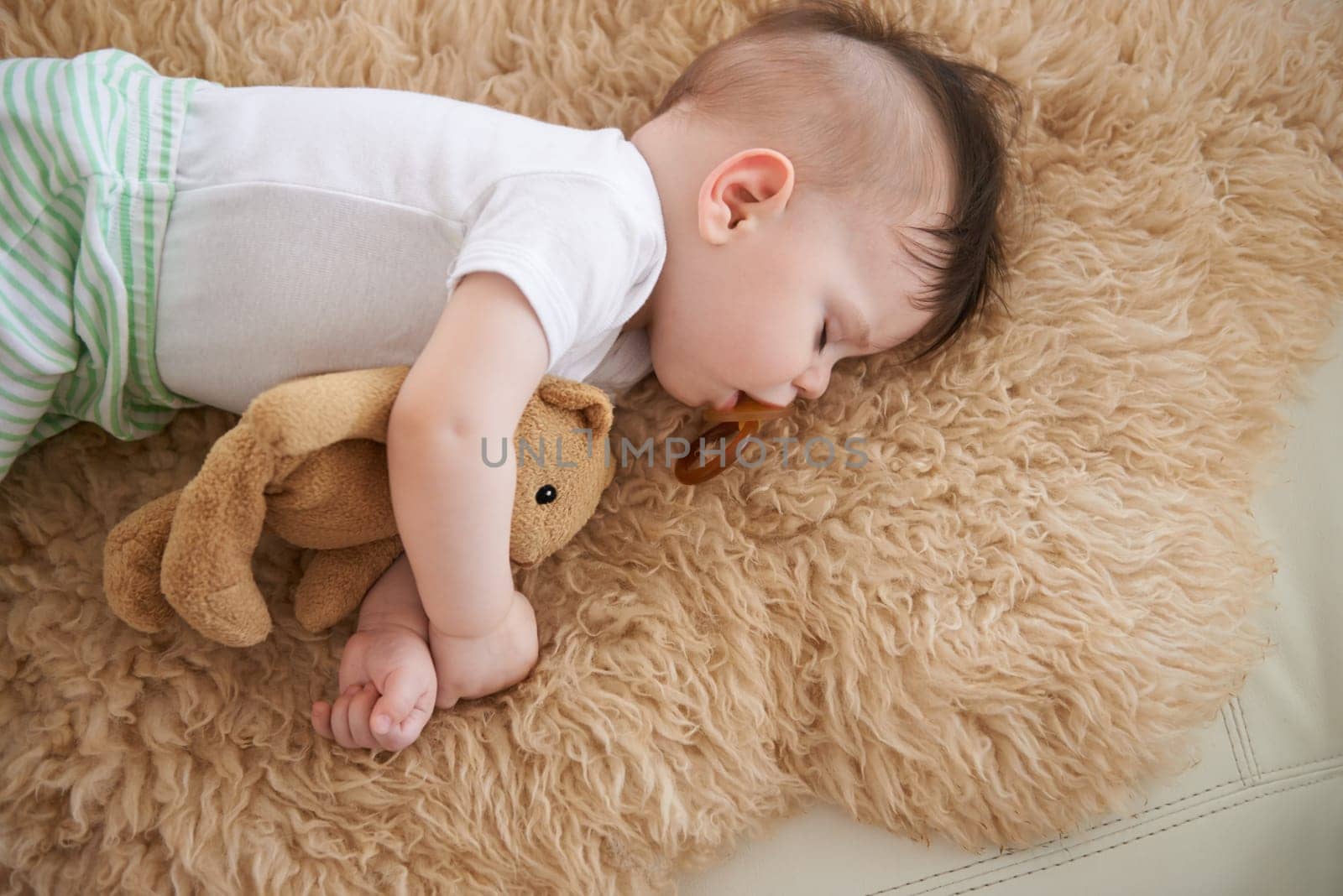 Toddler, sleep and home with teddybear in sofa to rest, tired and relax with dummy and dream. High angle, baby, and nap in couch for child development, growth and innocent with peace for bedtime. by YuriArcurs