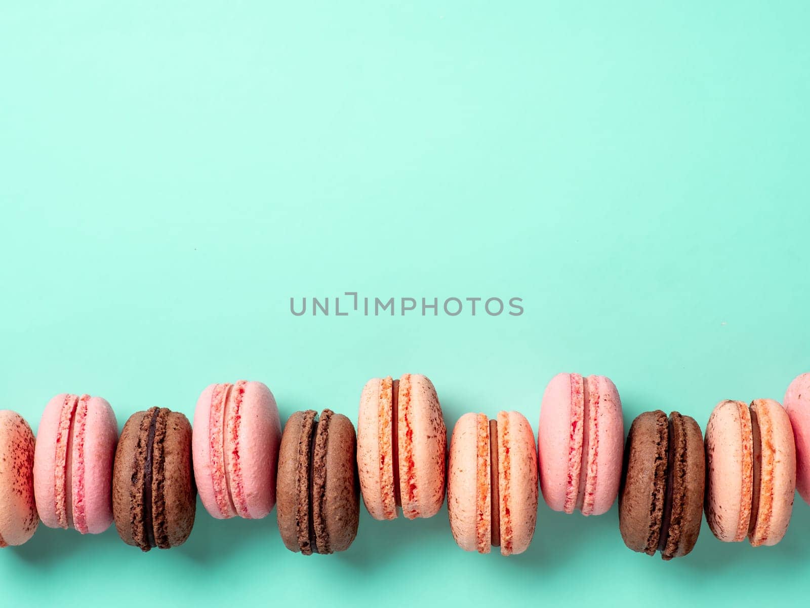 Macarons with copy space. Row of perfect french macarons or macaroons on blue turquoise background. Top view or flat lay