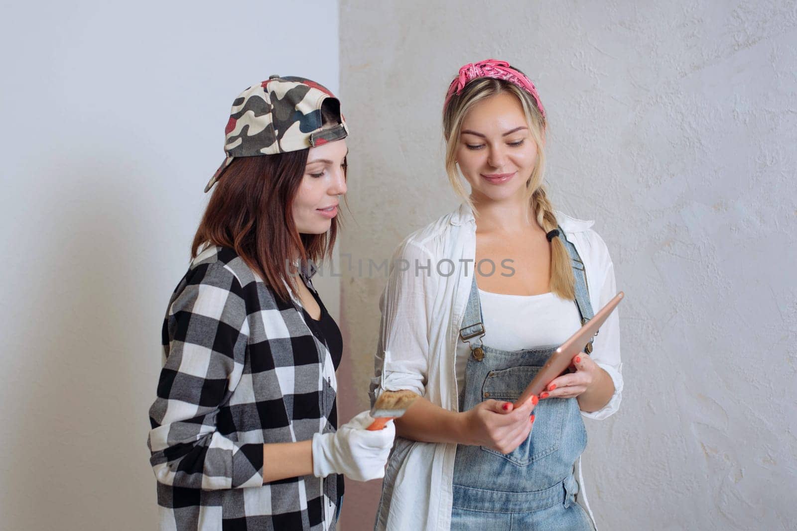 Home interior. Two cute girls designer and painter make repairs in the house.A team of decorators.