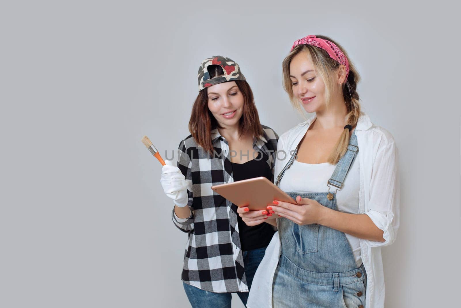 Home interior. Two cute girls designer and painter make repairs in the house.A team of decorators.