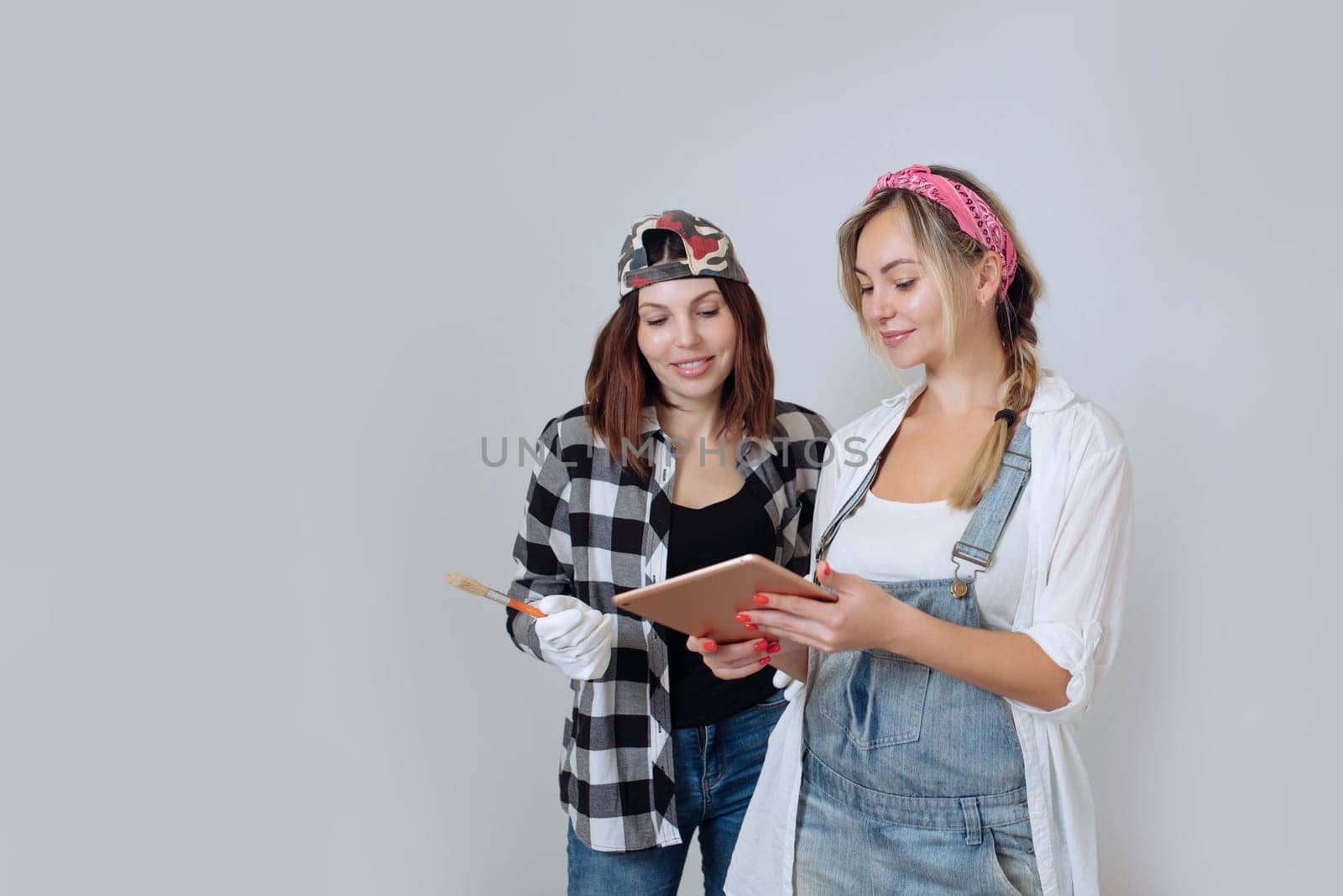 Home interior. Two cute girls designer and painter make repairs in the house.A team of decorators.