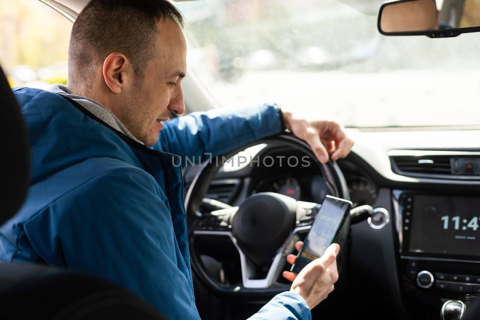 Man use mobile phone in the car, betting on sports.