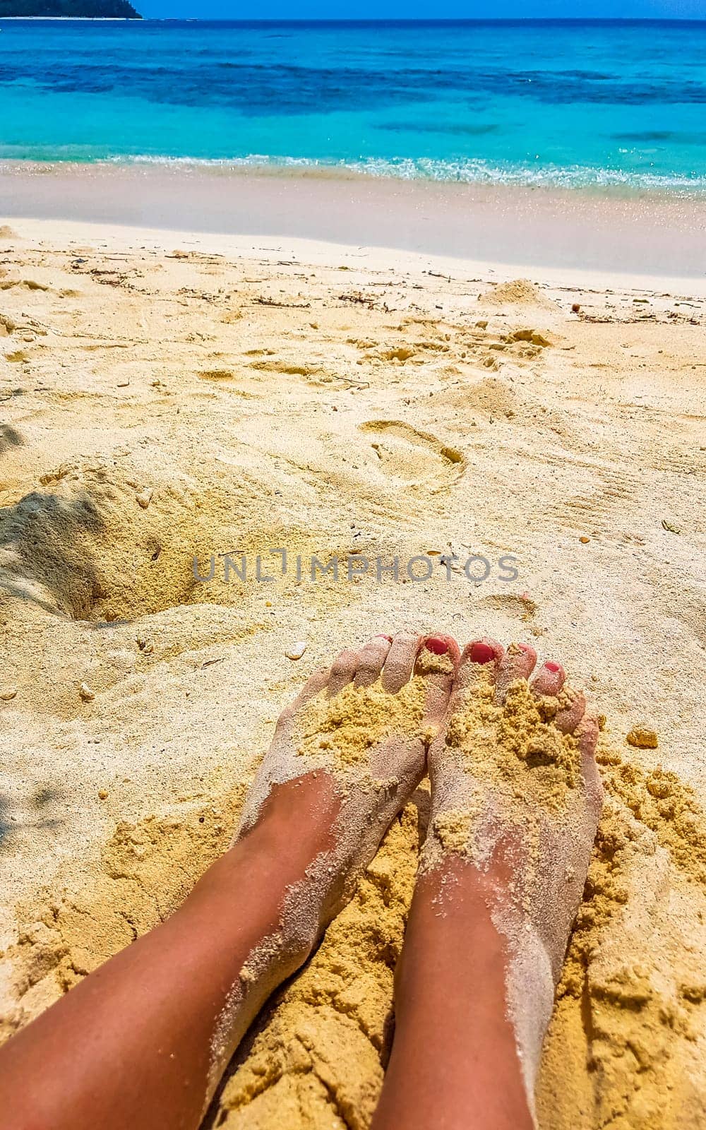 Beautiful sexy female legs on the beach on sand in the water on Rasdhoo island in Rasdhoo Atoll Maldives.