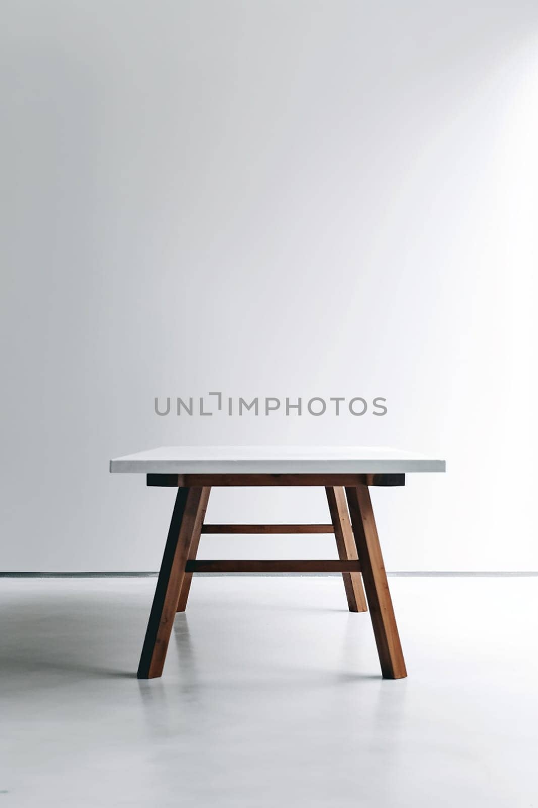 A minimalistic white table with wooden legs in a bright room.
