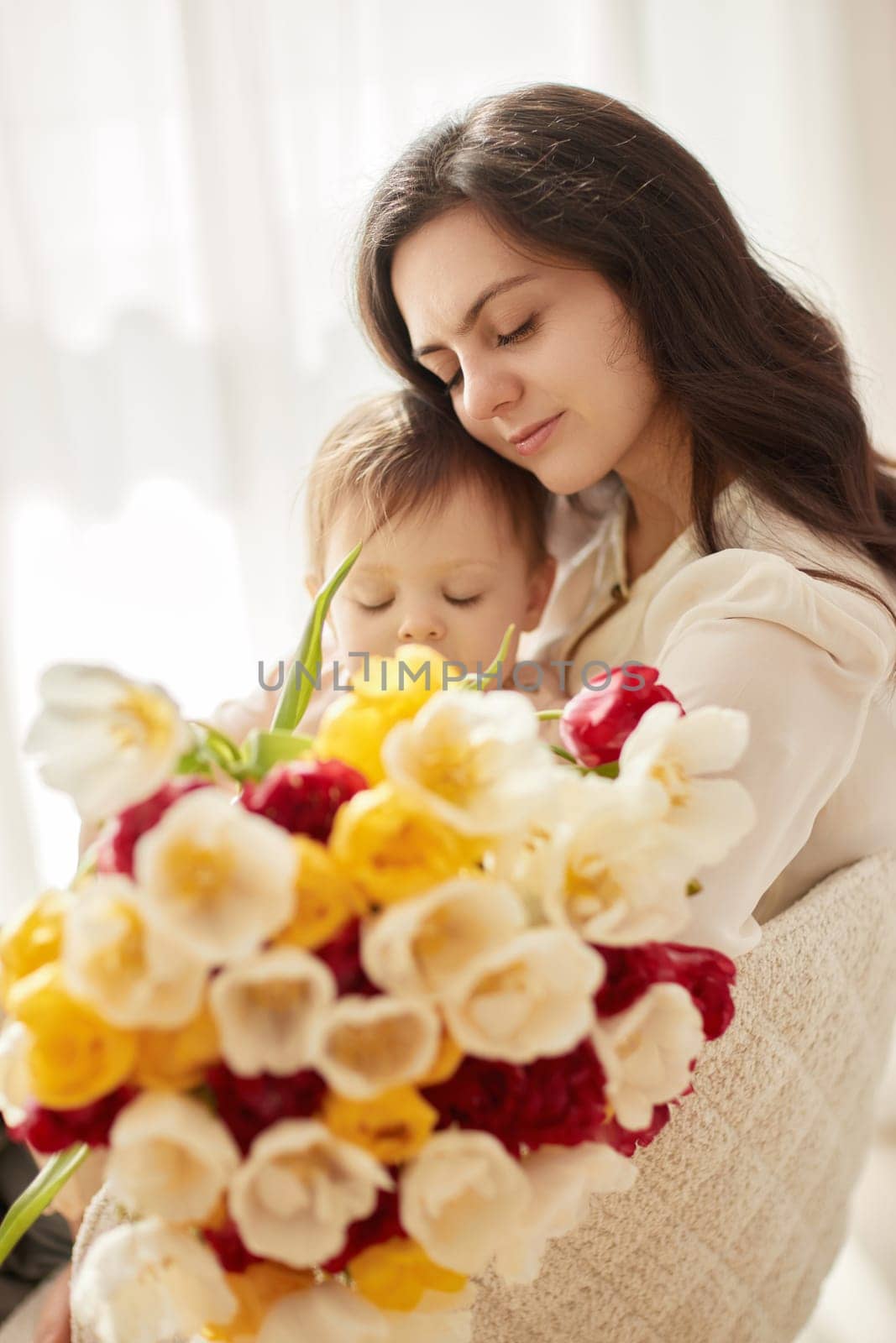 Cute little baby daughter and mom with flowers tulips. by erstudio