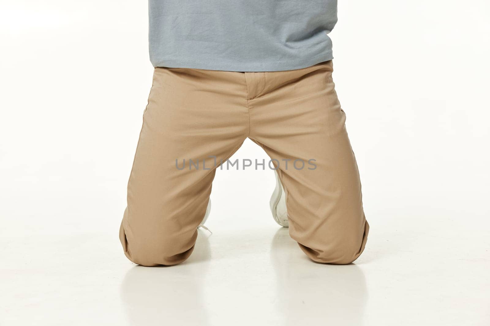 casual man standing on his knees on white studio background