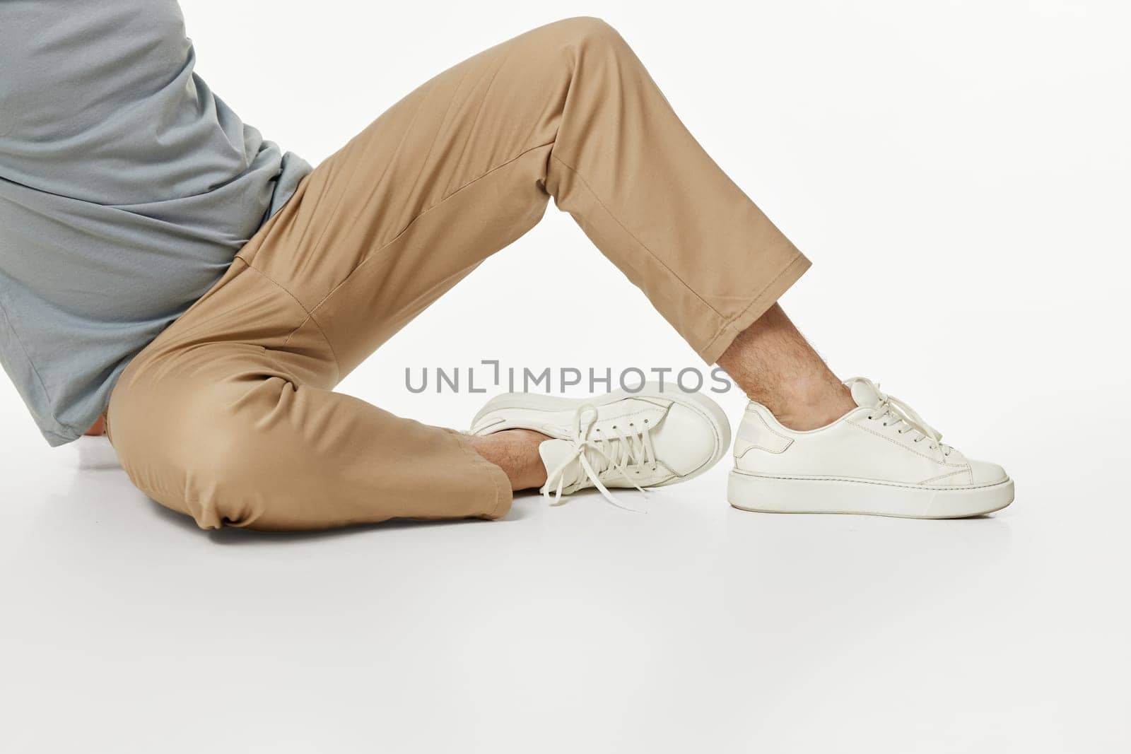 man wearing white sneakers and beige pants sitting on floor