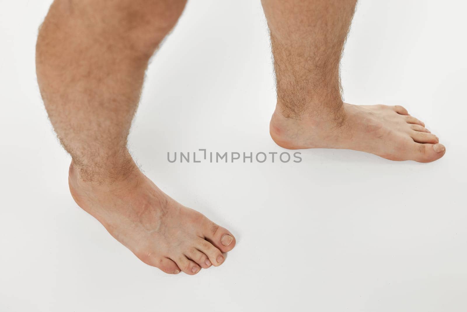 Barefoot male legs on white background. Body care concept.