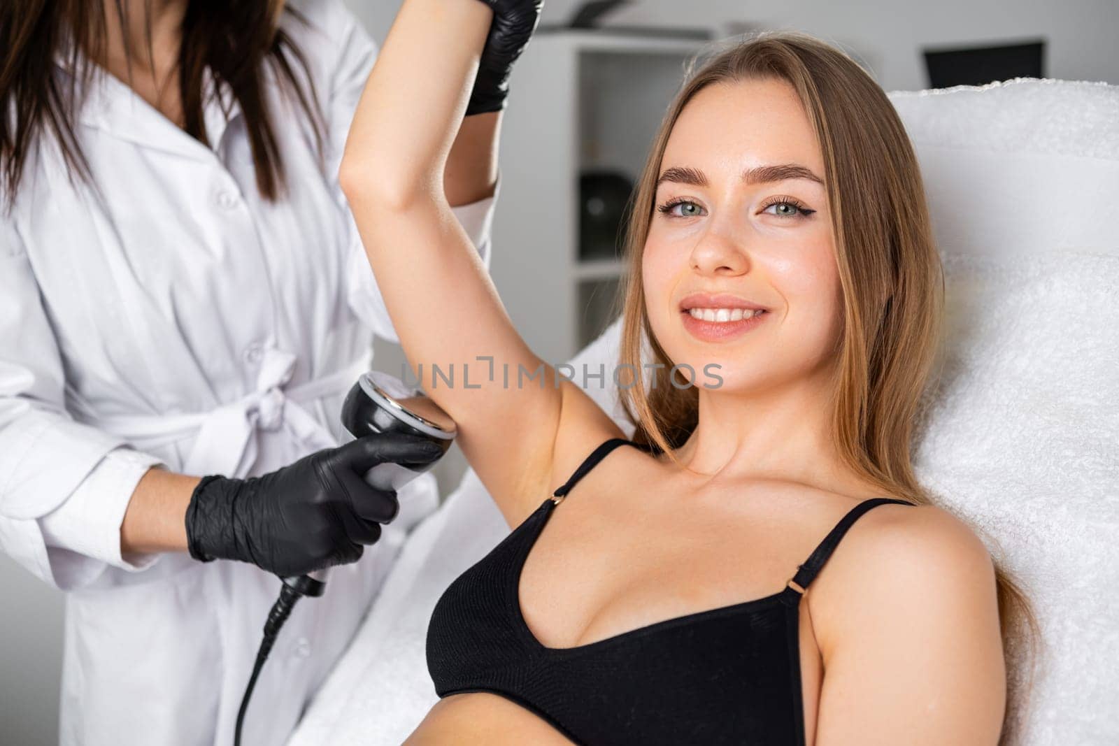 Portrait of a young blonde woman during ultrasound cavitation procedure in a beauty salon.