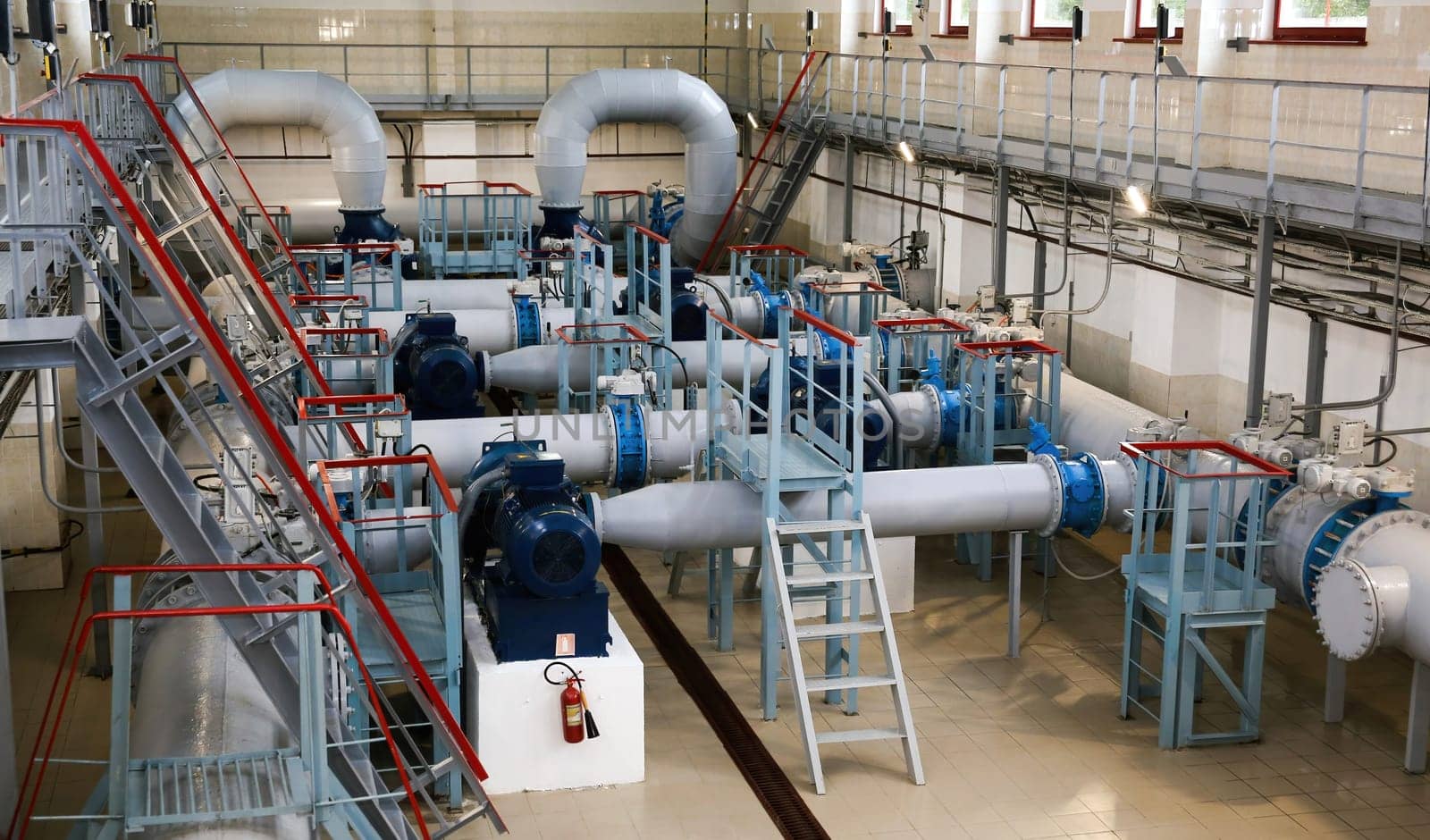 The industrial water pumping station features well-maintained pumps, pipes, and valves, brightly lit and showcasing precise engineering in efficient water management.