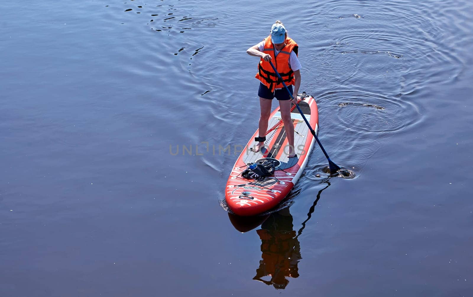 Paddleboarding on lake, aerial view. Stand up paddle boarding (SUP) water sport. Adventure on river on Stand up paddle board. Summer fun, holidays travel on SUP board. Active lifestyle on water.