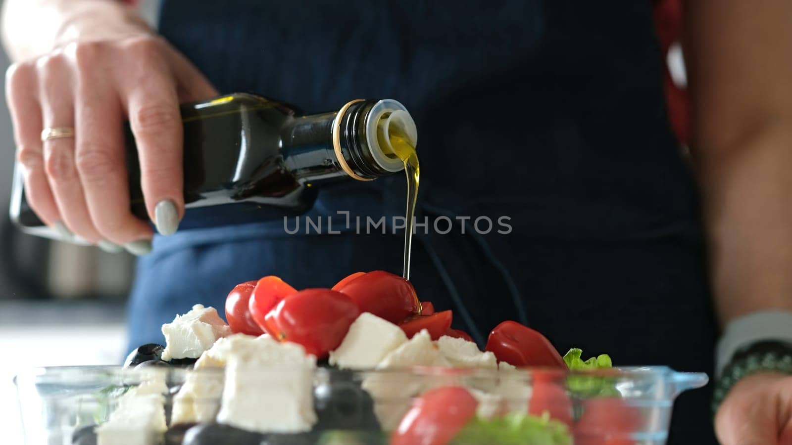 Female Hands Drizzle Oil On Greek Salad. Delicious Vegetarian Meal