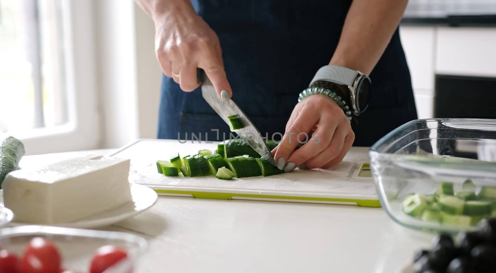 Female Hands Slicing Cucumber For Greek Salad by tan4ikk1