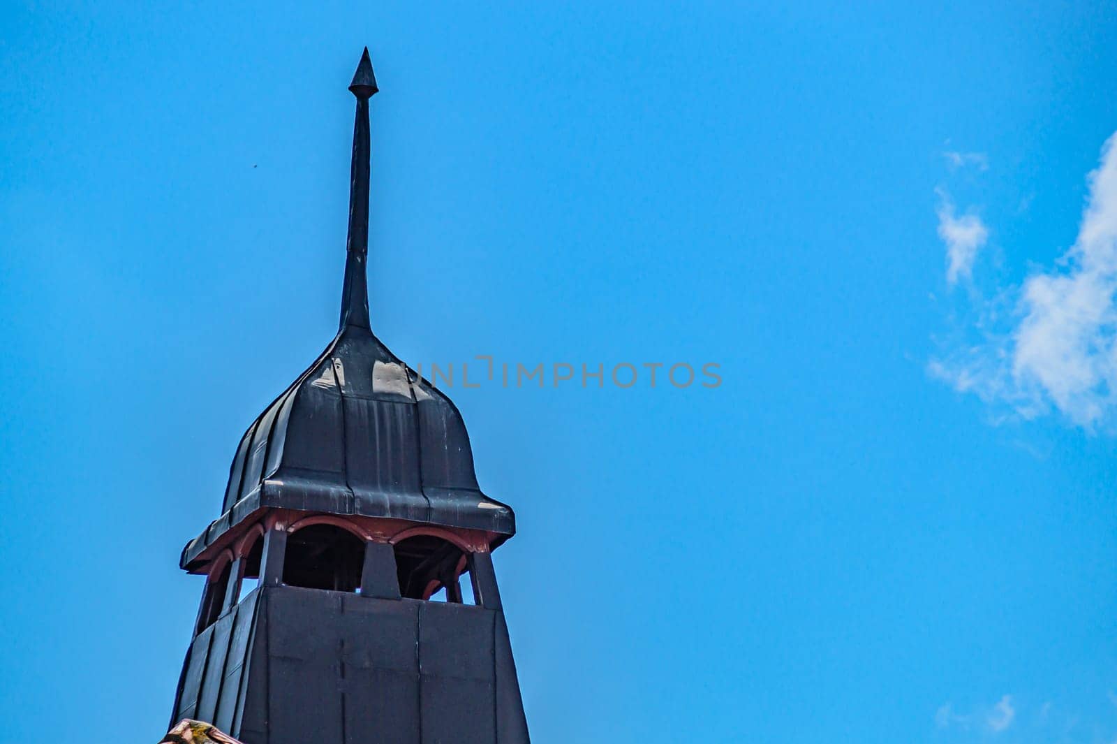 An ancient Gothic tower. A black tower with a tip, a place for archers, for defense under blue sky. Kharkiv Ukraine 05-05-2023