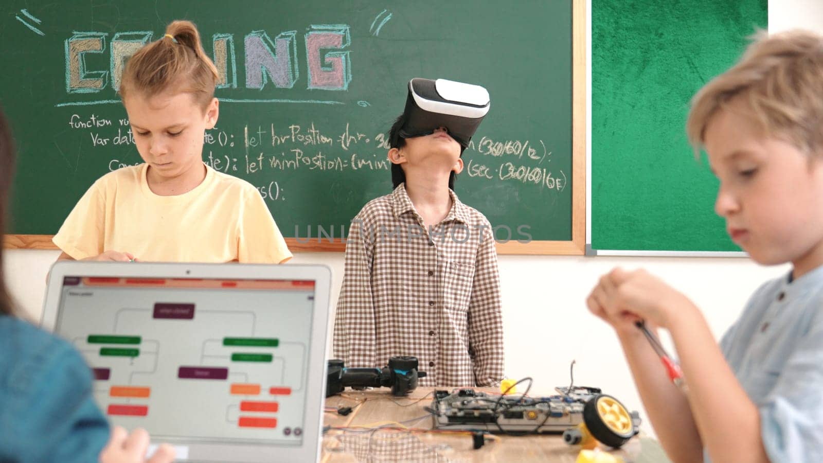 Energetic child wearing Vr headset while enter virtual world at classroom. Student programing system while generated AI to code engineering prompt software while boy fixing electronic board. Pedagogy.