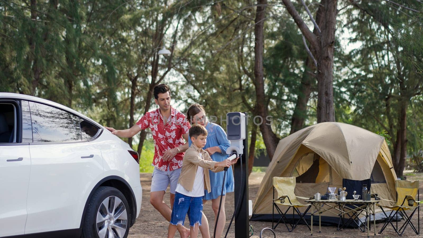 Lovely family recharge EV car with EV charging station in campsite. Perpetual by biancoblue