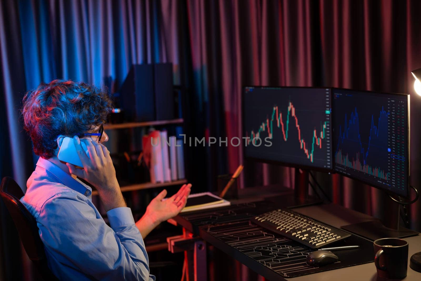 Young business trader calling to broker, consulting profit currency rate investment on global market online on pc screen in real time at neon light modern office. Concept of stock exchange. Gusher.