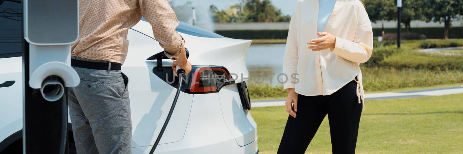 Young couple recharge EV car battery at charging station. Expedient by biancoblue