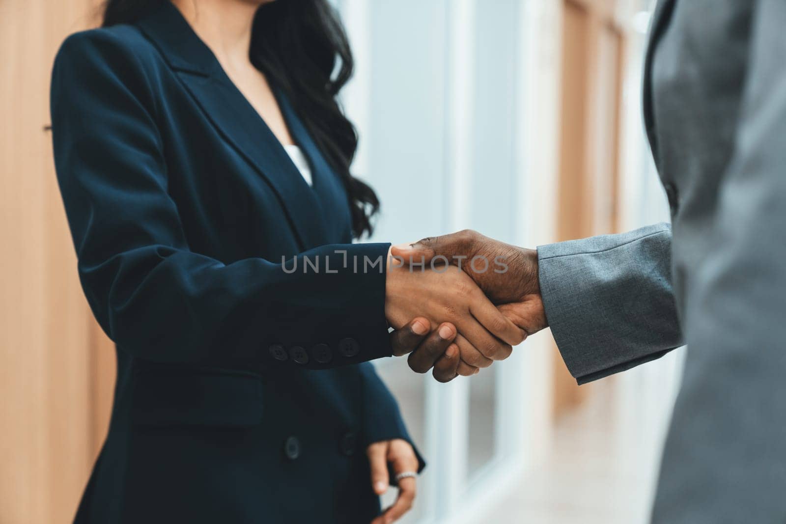 Closeup of business hands shaking between businesswoman and professional male leader at modern office corridor. Represented unity, corporate, collaborate, teamwork cooperation, joining. Ornamented.