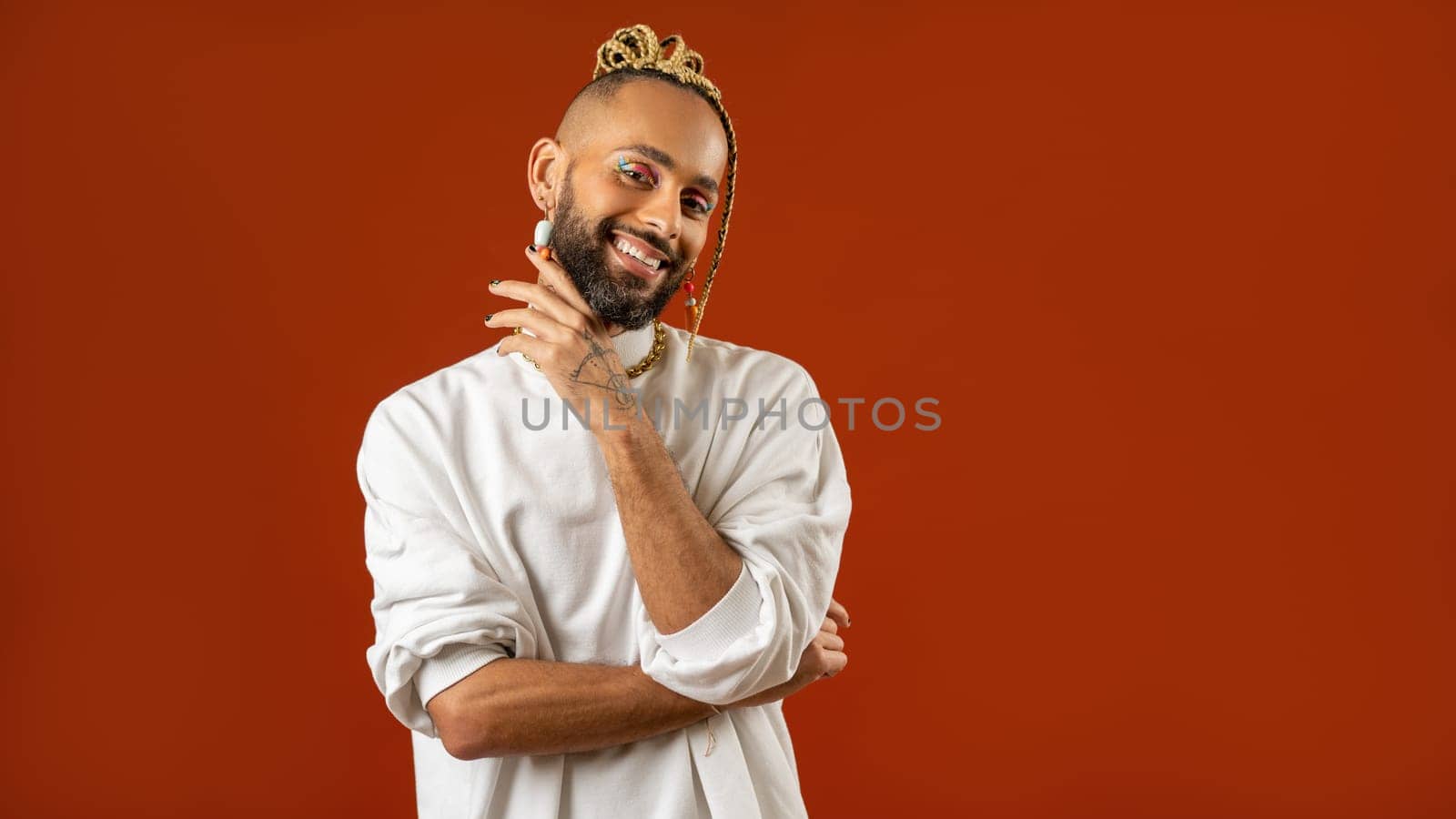 Make up artist. Black afro-american gay man with bright make-up in white clothes smiling looking at camera isolated on red background studio portrait Fashion makeup lgbt concept. Banner format