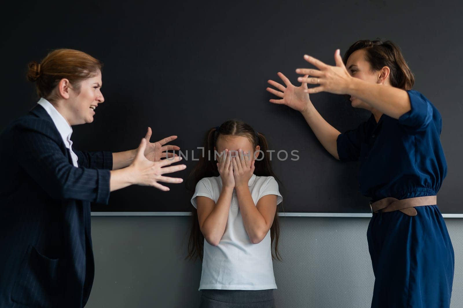 A female teacher and a student's mother yell at each other at the blackboard. The schoolgirl is crying. by mrwed54
