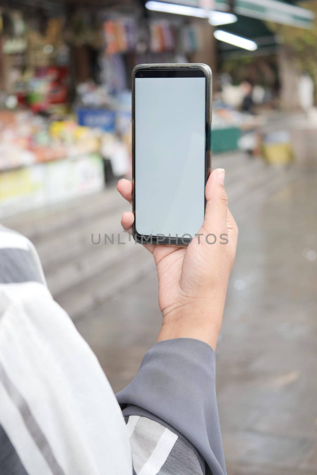 holding smart phone with empty screen with blurred cafe street background. by towfiq007