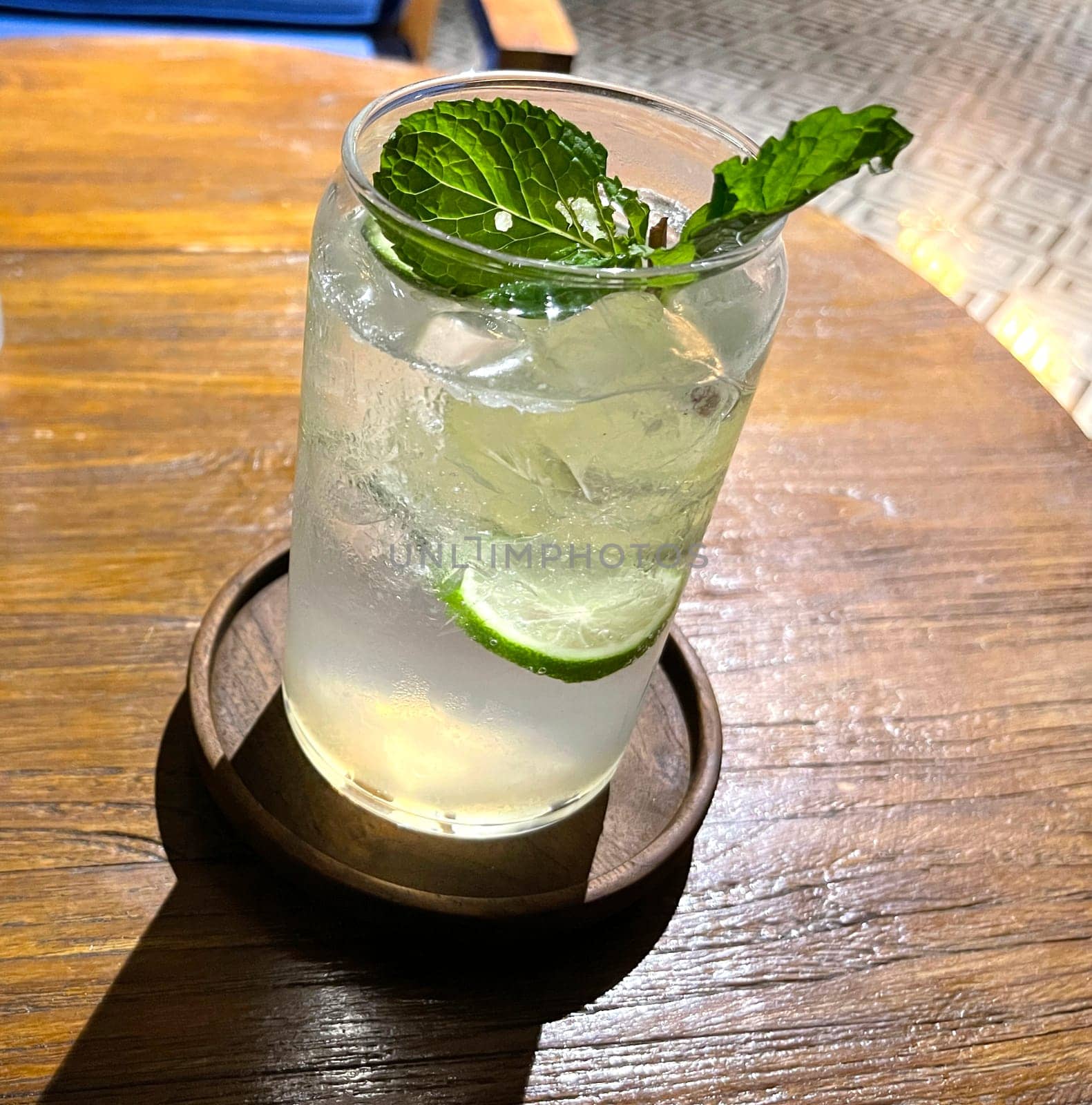 Selective focus, Delicious refreshing summer mojito with ice, lime and mint in a glass with grops. wood background. Copy space. Cold lemonade, tonic.