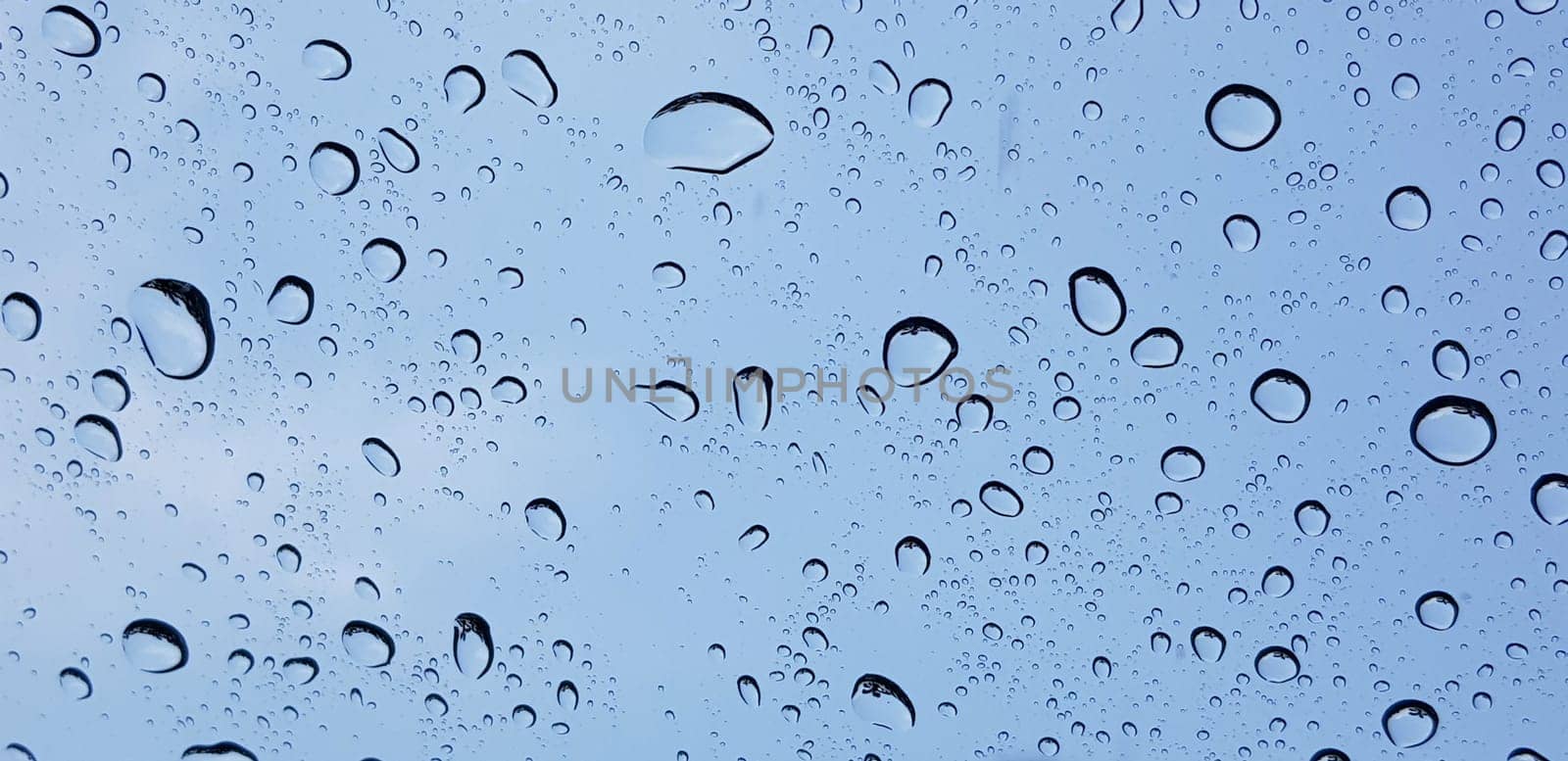 Water droplets perspective through window glass surface against blue sky good for multimedia content by antoksena