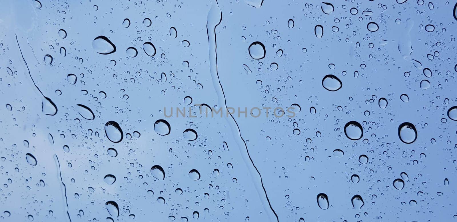 Water droplets perspective through window glass surface against blue sky good for multimedia content by antoksena