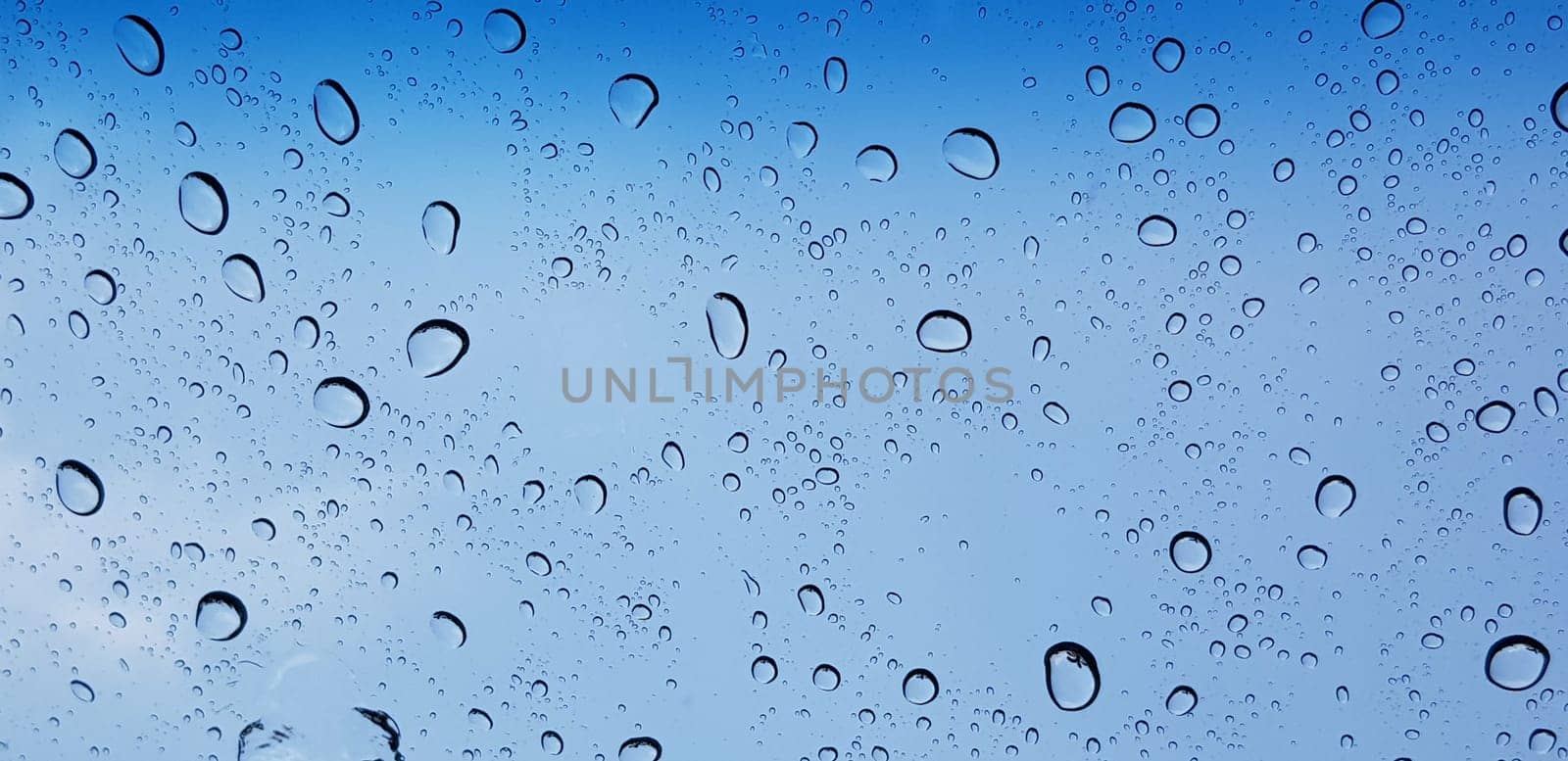 Water droplets perspective through window glass surface against blue sky good for multimedia content by antoksena