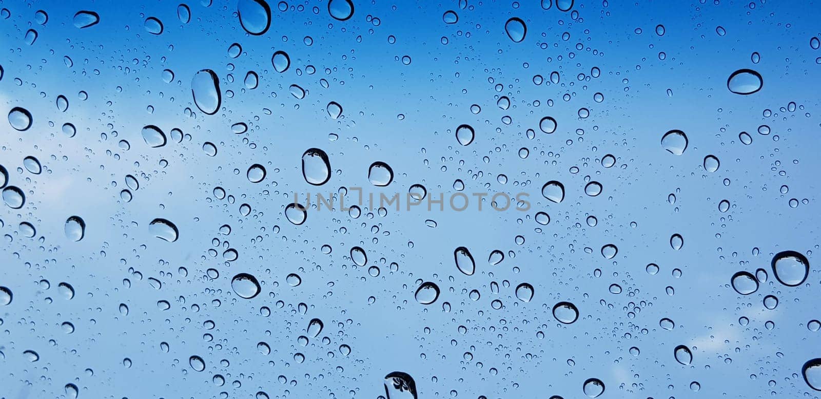Water droplets perspective through window glass surface against blue sky good for multimedia content by antoksena