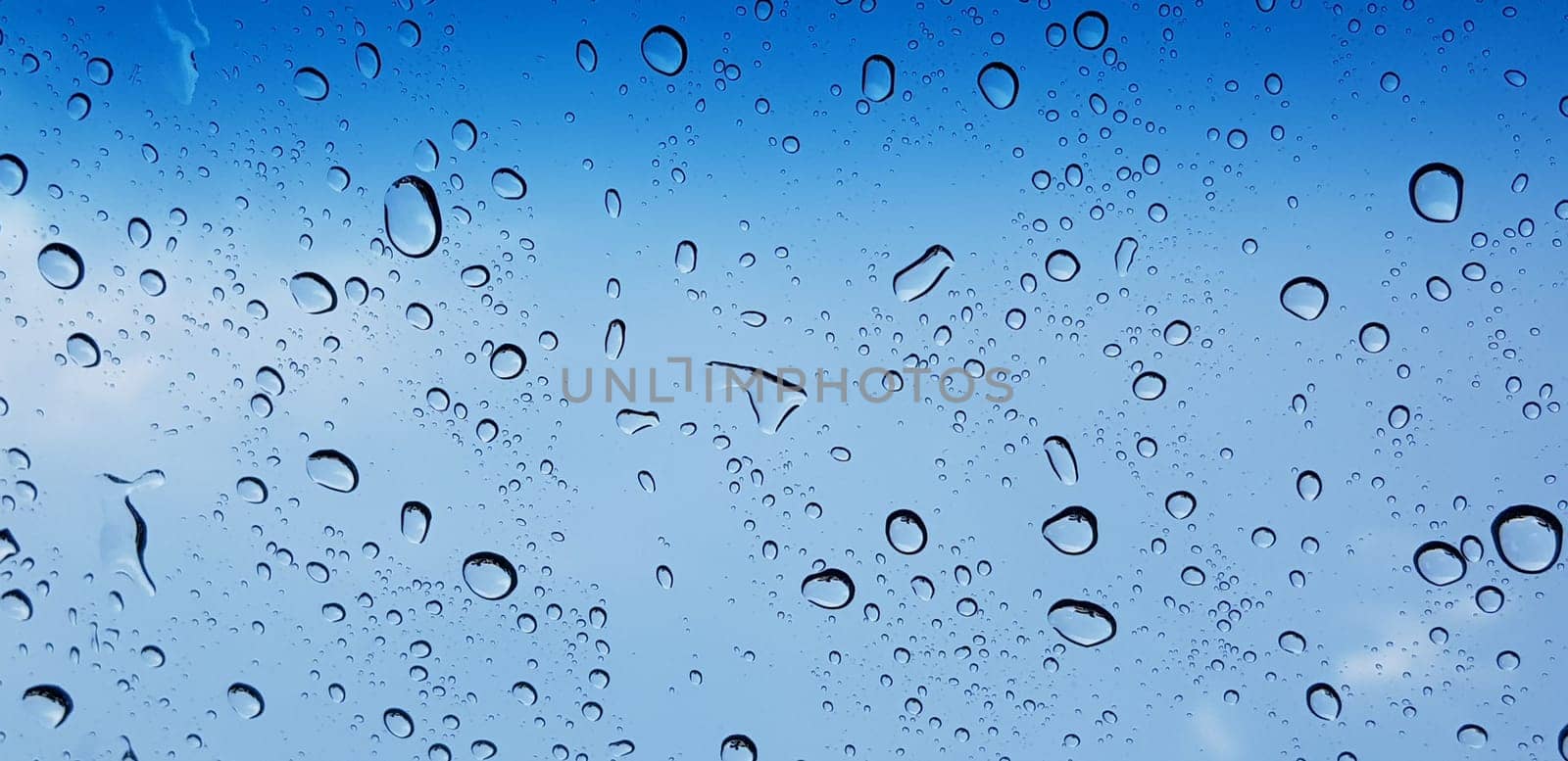 Water droplets perspective through window glass surface against blue sky good for multimedia content by antoksena