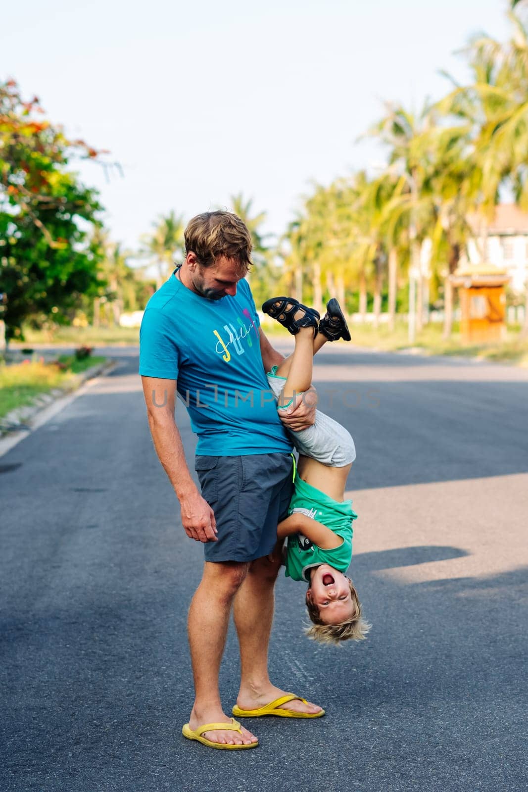 Father son have fun. Man holds child's leg upside down head. Joy happiness childhood paternity delight by nandrey85