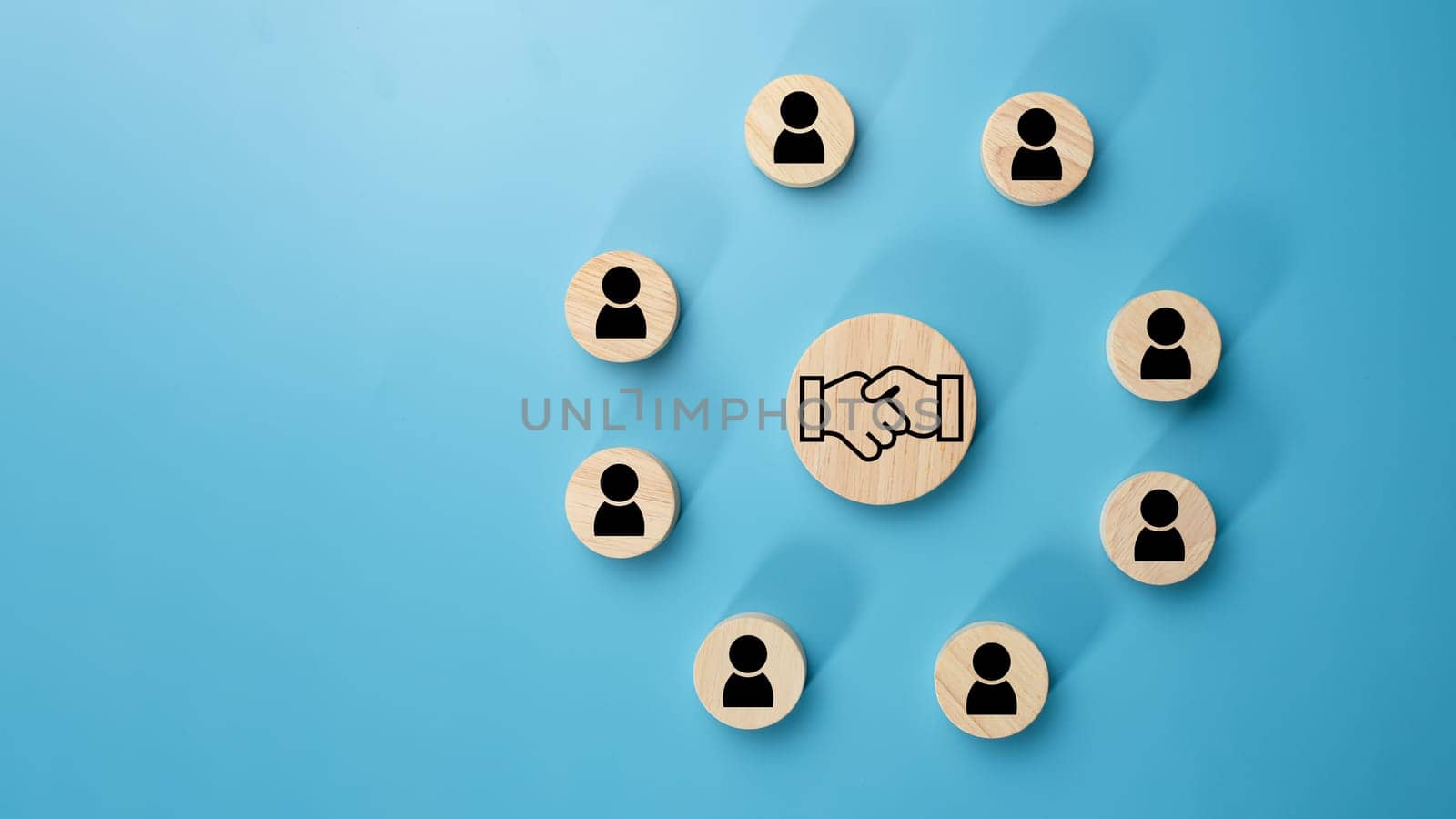 Team management concept, Human resources, Recruitment concept, HRM administration or human resource management concept, The handshake icon in a circular wooden board placed on a light blue background. by Unimages2527