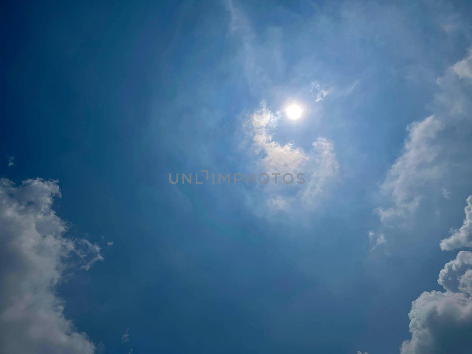 Heavenly white clouds on the blue sky with the sun appeared perfect for multimedia texture or background