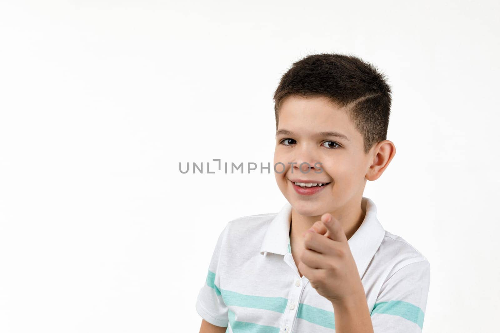 Cute smiling little boy in striped t-shirt pointing camera on white background. child pointing at you.
