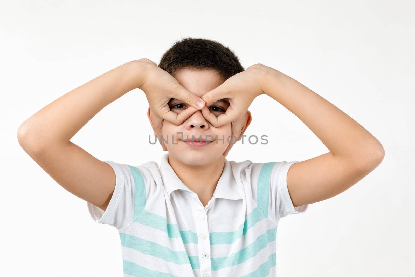 happy funny little child boy in striped t-shirt having fun on white background. facial expression. kid making mask or making gesture like binoculars