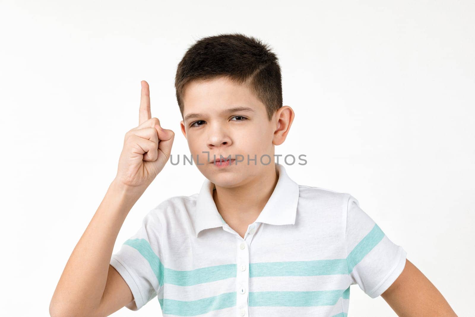 little smart child boy in t-shirt looking to camera and pointing up on white background. Human emotions and facial expression