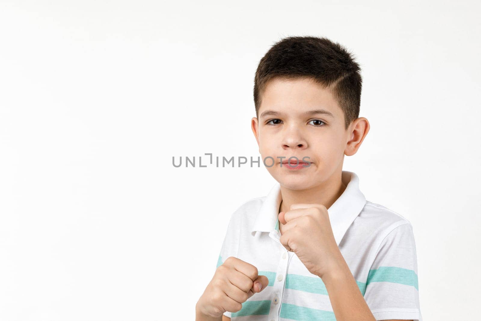 angry little child boy mad raising fist over white background. Human emotions and facial expression