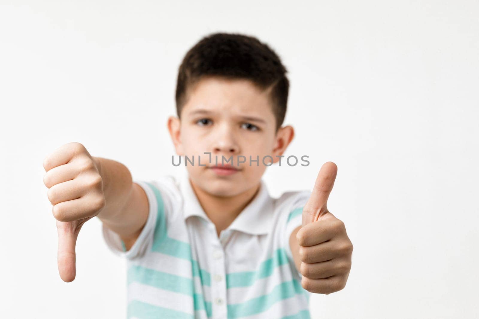 Cute little child boy showing the thumbs down and thumbs up gesture on white background. choice