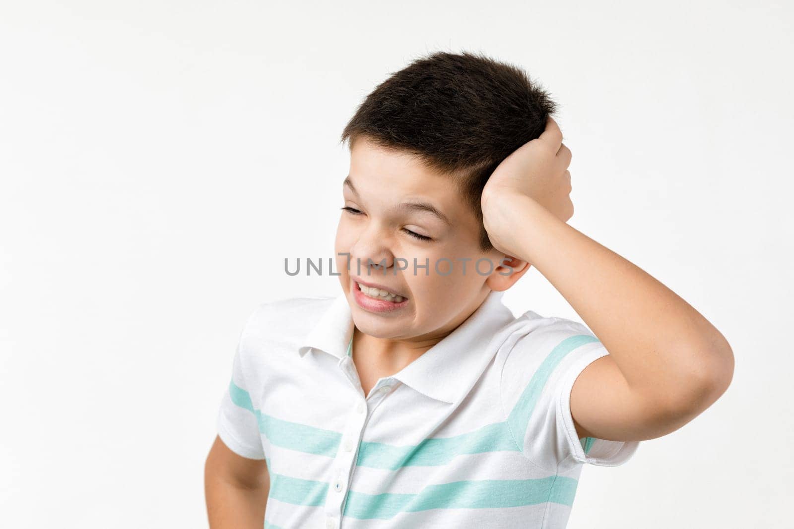 Cute little child boy in striped t-shirt thinks about something on white background. Human emotions and facial expression