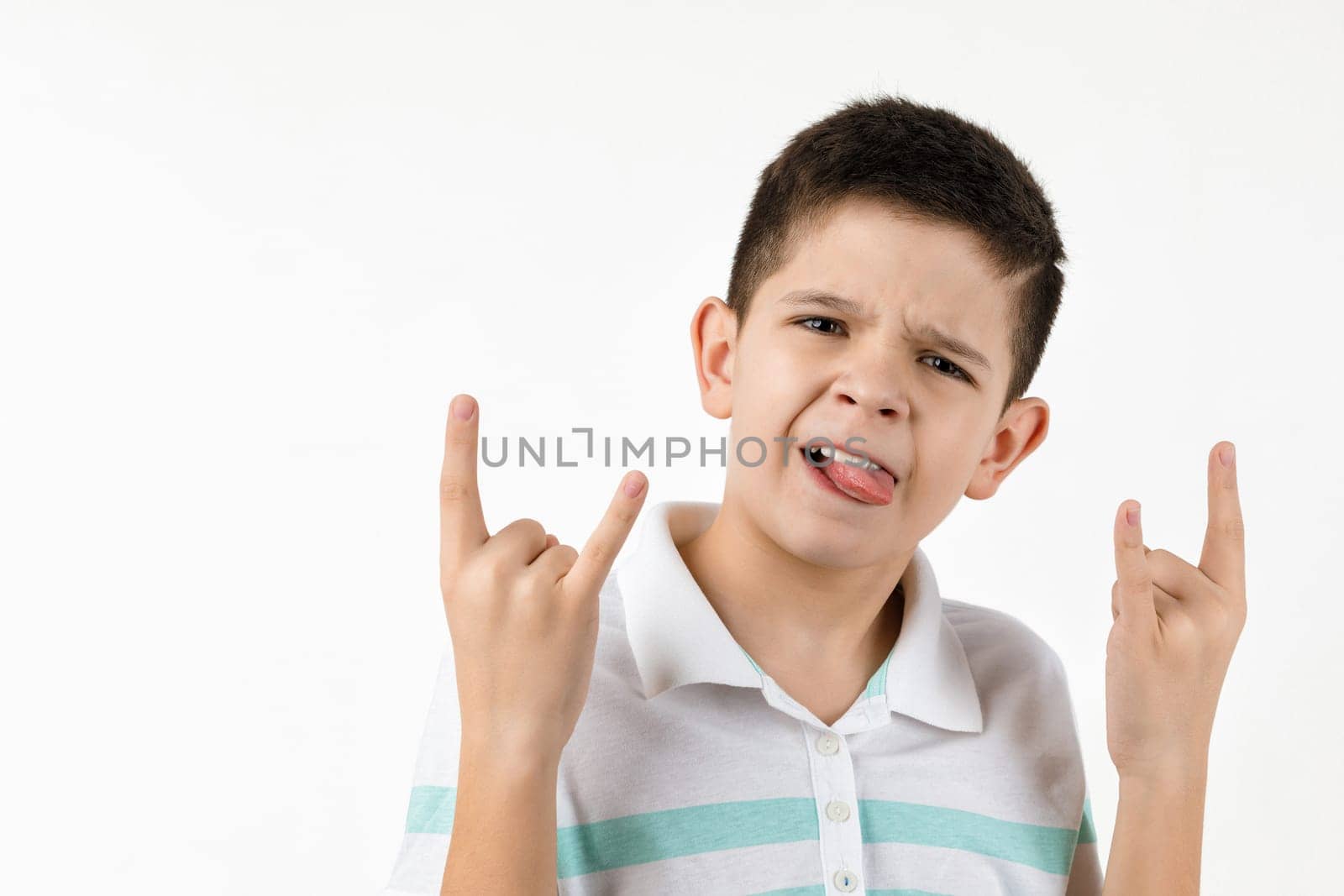 Cute little child boy in striped t-shirt making Rock gesture on white background.