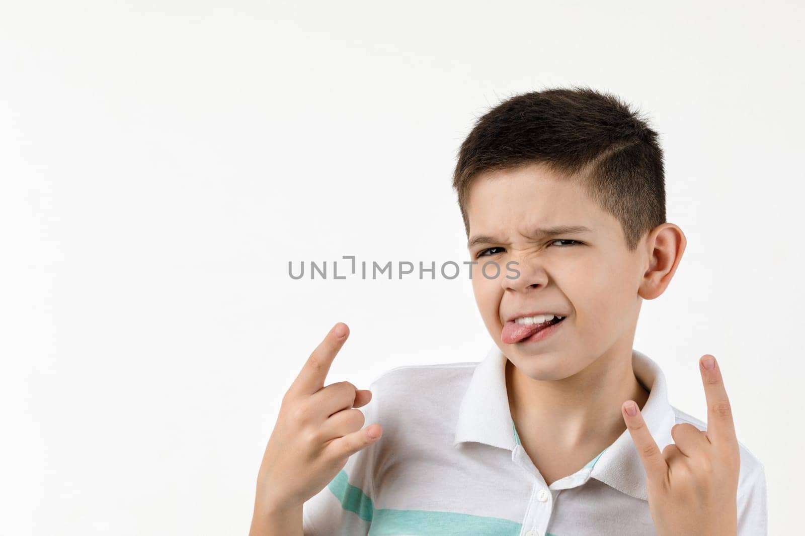 Cute little child boy in striped t-shirt making Rock gesture on white background.