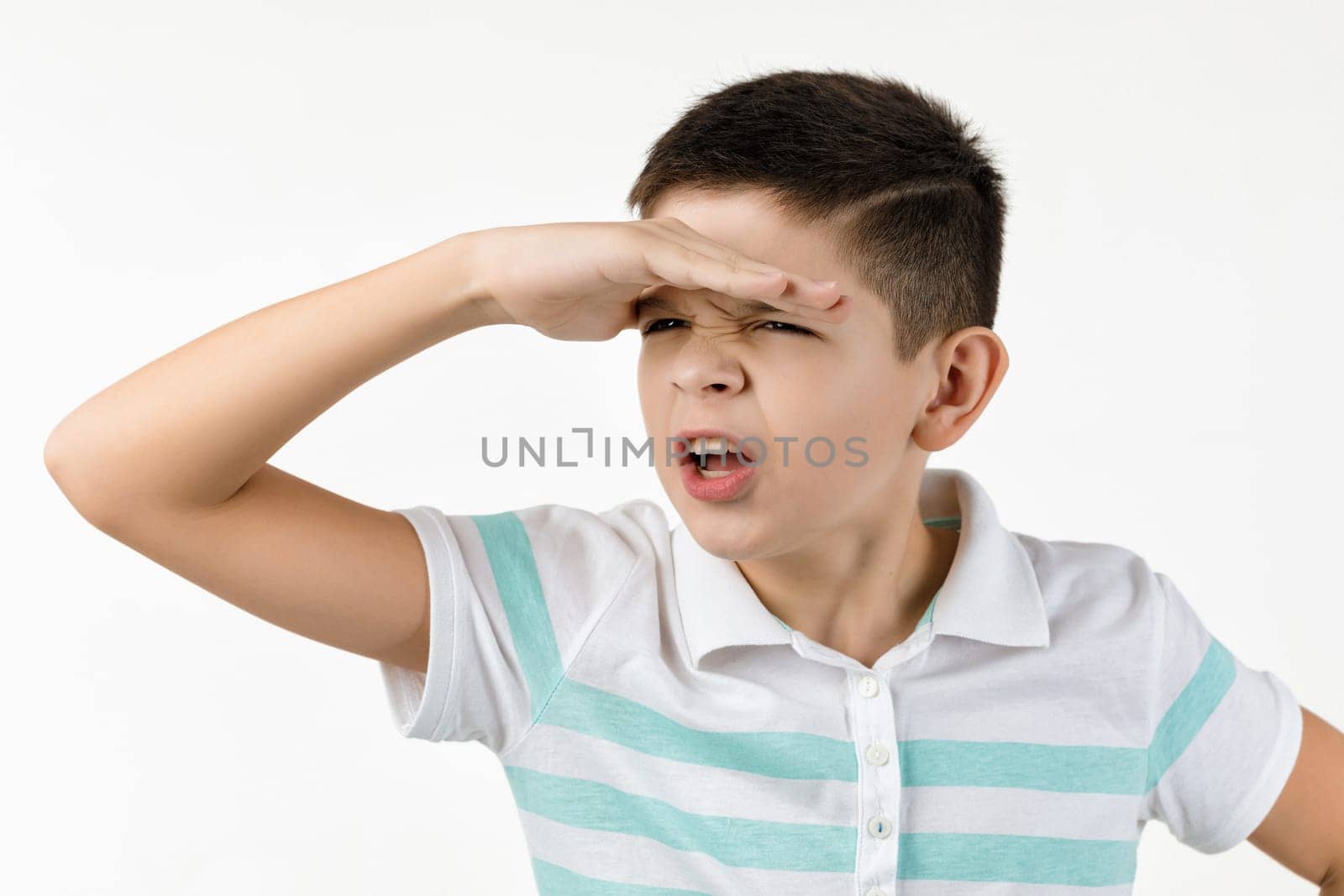 Cute little child boy in striped t-shirt looking into the distance on white background.