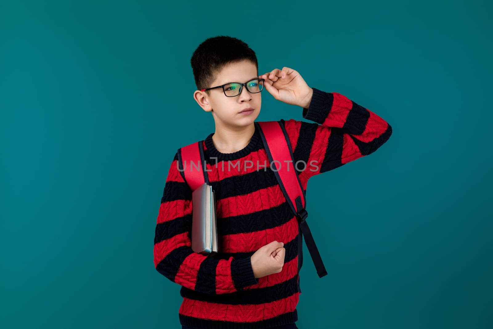 little cheerful school boy wearing glasses holding a book over blue background